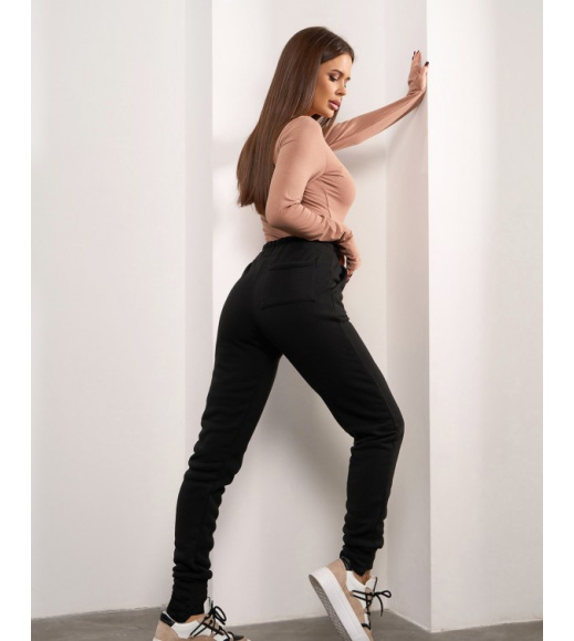 Чорні штани з асиметричними манжетами.